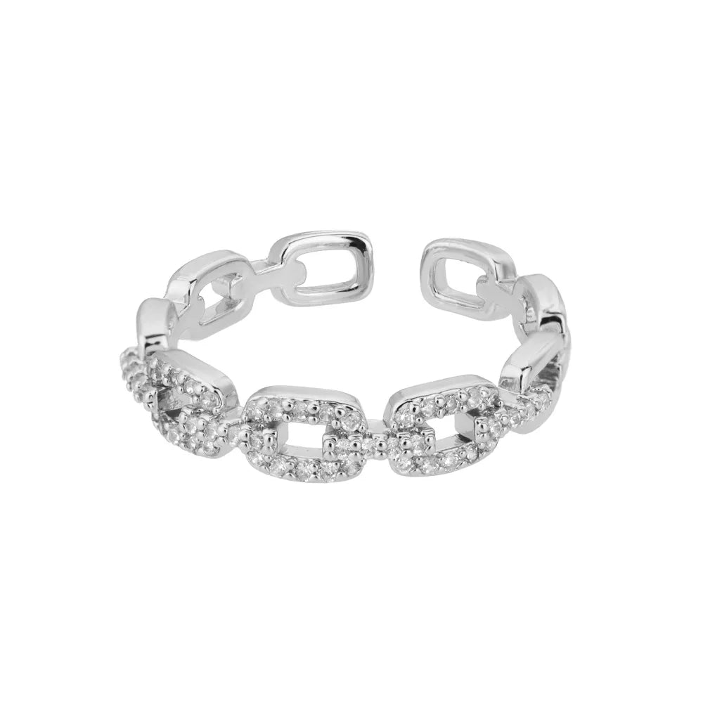 Classic Zircon Twist Chain Rings em ouro com detalhes em zircão brilhante sobre fundo de tecido bege.